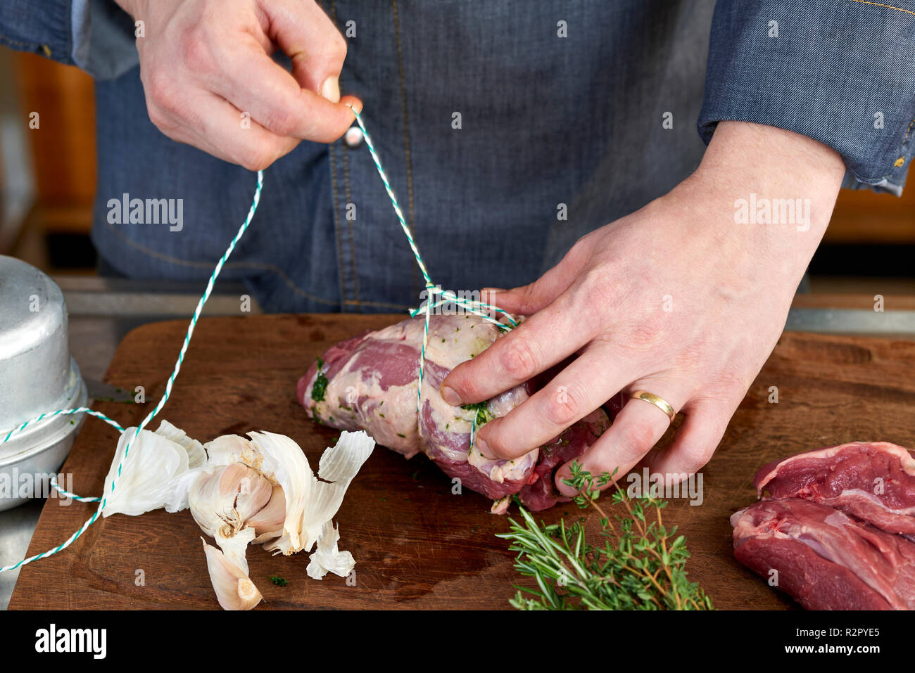 Serie di foto e passo-passo per la preparazione di una gamba di agnello riempito con erbe e verdure provenzale utilizzando un robot da cucina (Thermomix ® e Varoma ®), trussing la gamba di agnello Foto Stock