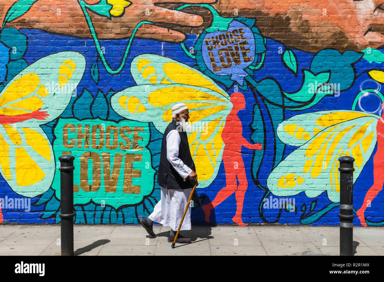 Inghilterra, Londra, Shoreditch, Brick Lane, anziani uomo musulmano oltrepassando la Street Art Foto Stock