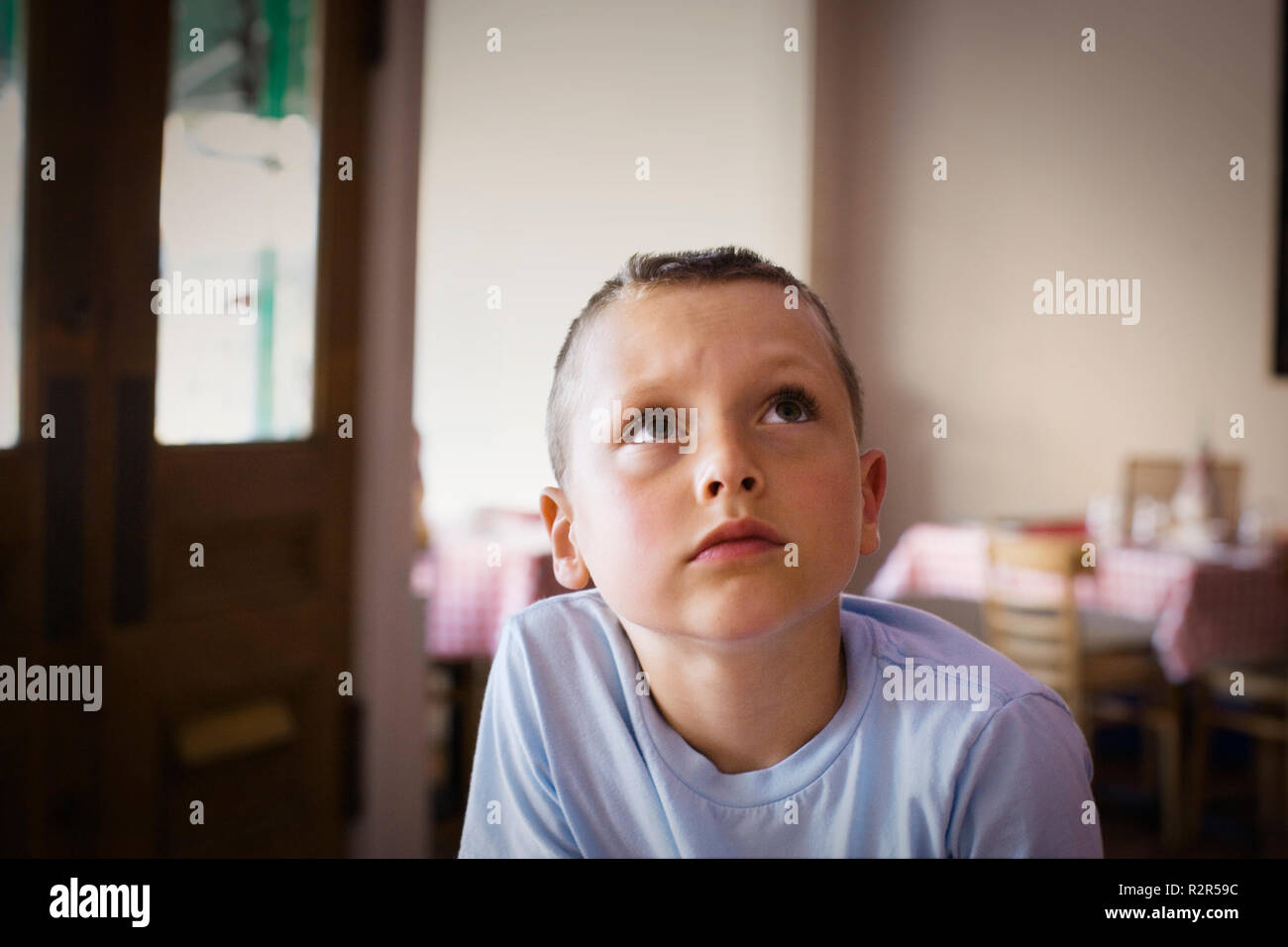 Ragazzo seduto in una casa guardando verso l'alto. Foto Stock