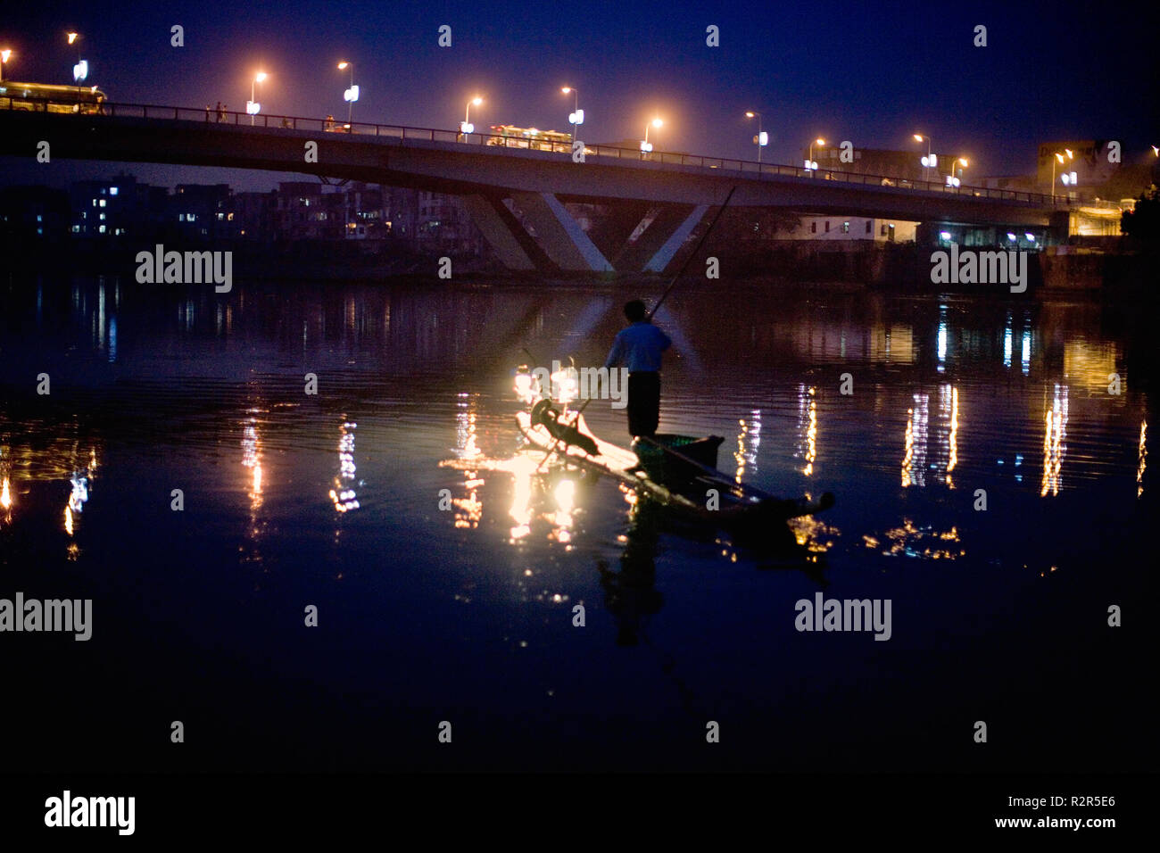 L'uomo spingendo una barca lungo un fiume di notte. Foto Stock