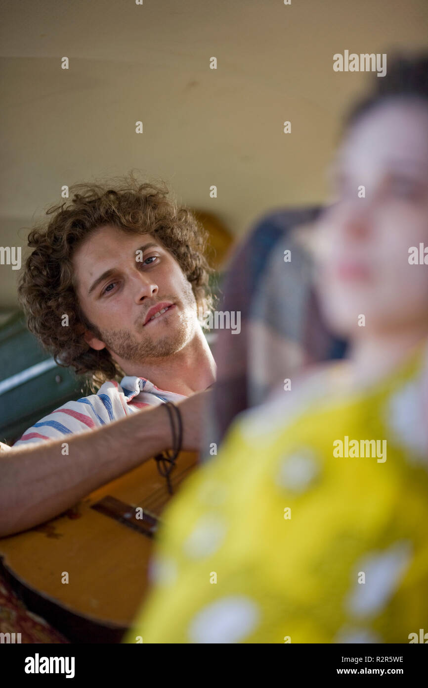 Giovane uomo di suonare una chitarra all'interno di un furgone. Foto Stock