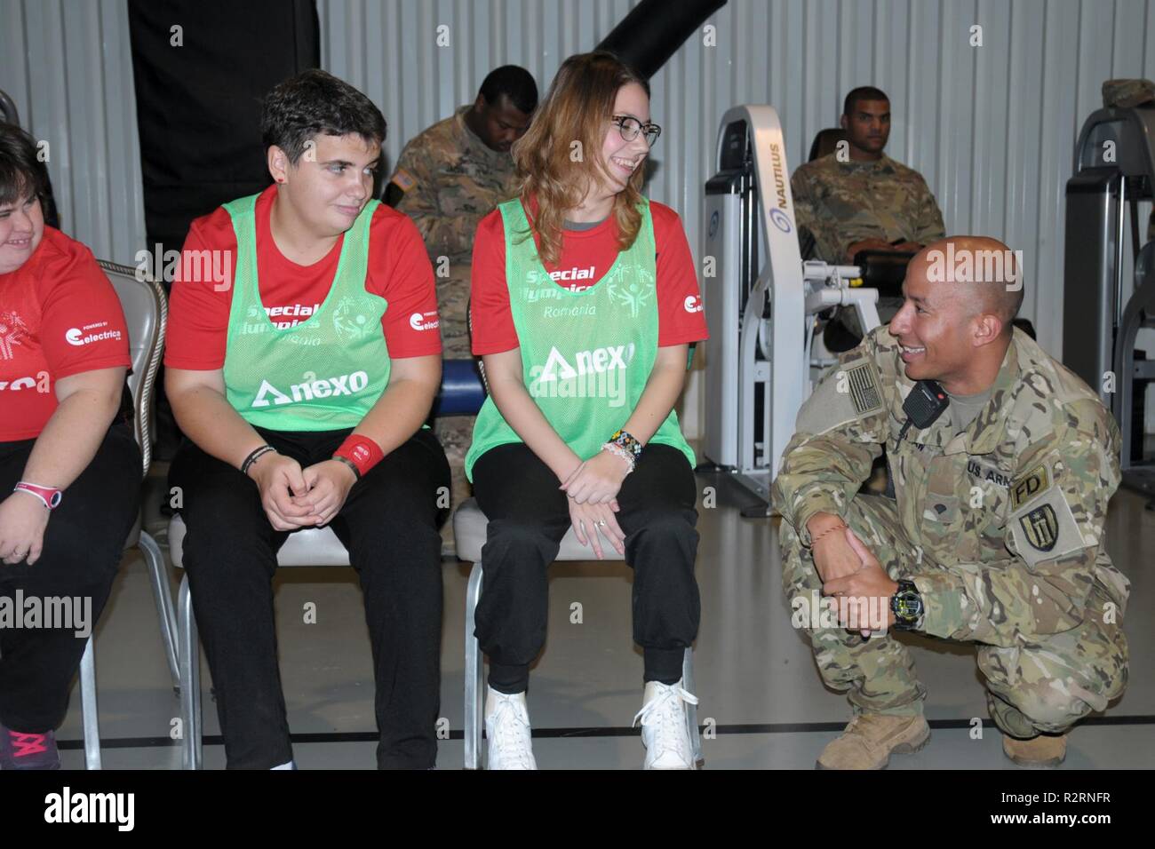 Stati Uniti Army Spc. Darnell Shaw, un vigile del fuoco con il 382 pompiere distacco, incoraggia gli atleti a Special Olympics della Romania evento ospitato a Mihail Kogalniceanu Air Base, Romania, nov. 6, 2018. Oltre 100 spettatori hanno seguito speciale 32 atleti olimpici e personale di base tra cui Stati Uniti e forze canadesi competere nel campo di bocce, ping pong, basket, roller e ginnastica. Foto Stock