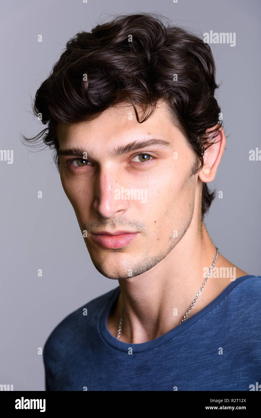 Volto del giovane brasiliano bello uomo contro uno sfondo grigio Foto Stock