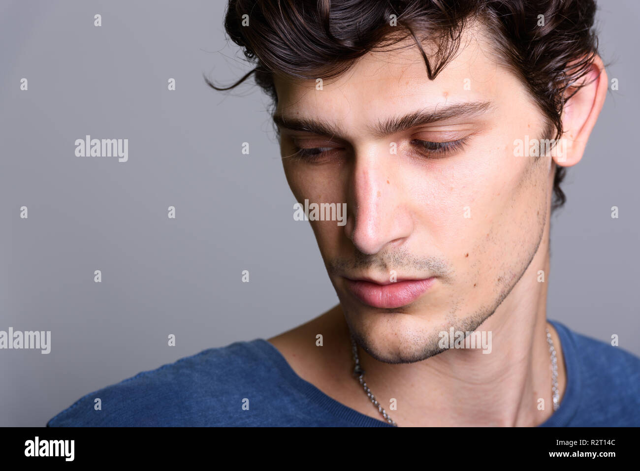 Ravvicinata di un bel giovane uomo brasiliani pensando mentre guardando verso il basso Foto Stock