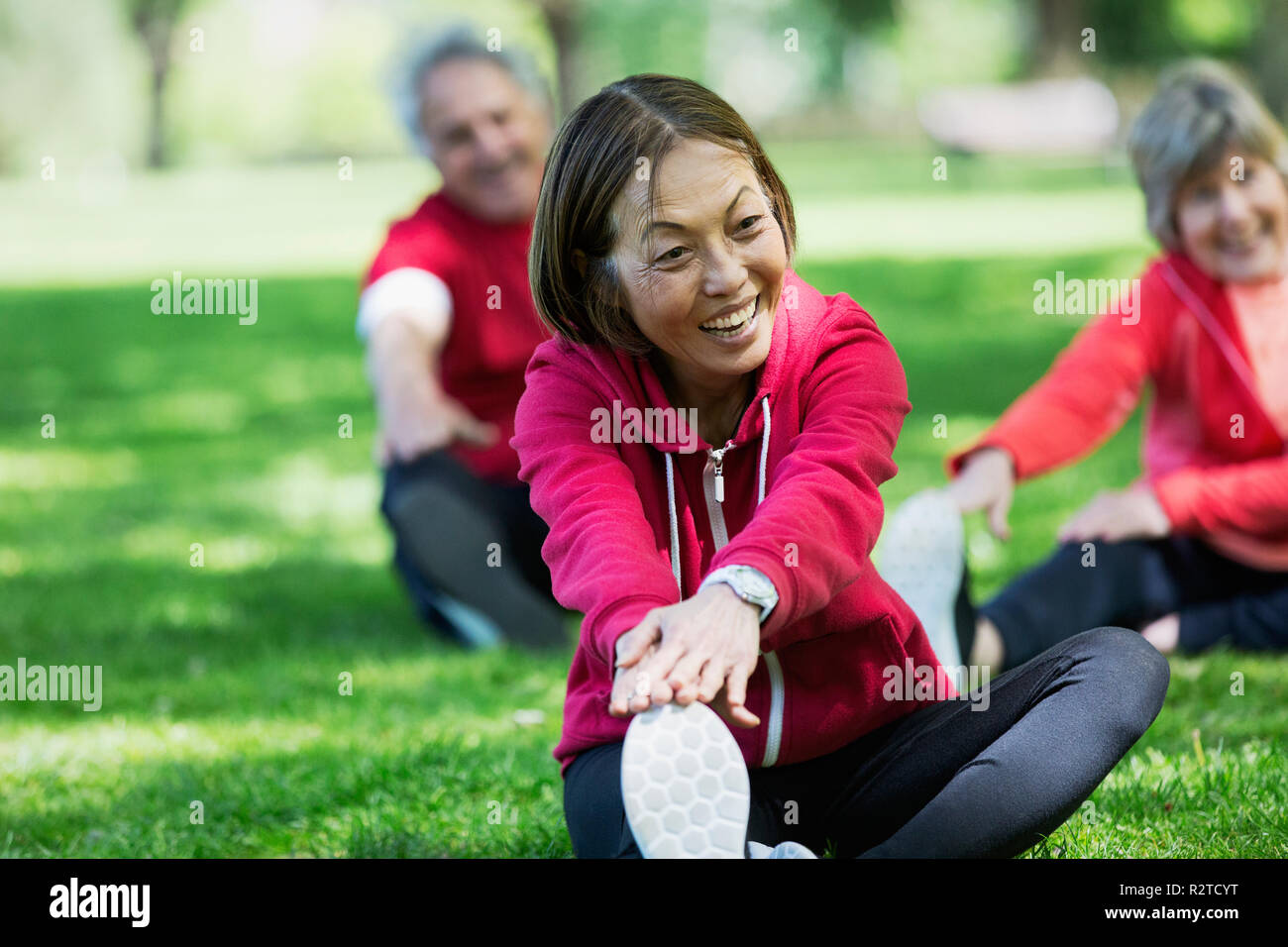 Felice attiva donna senior di allungamento della gamba in posizione di parcheggio Foto Stock