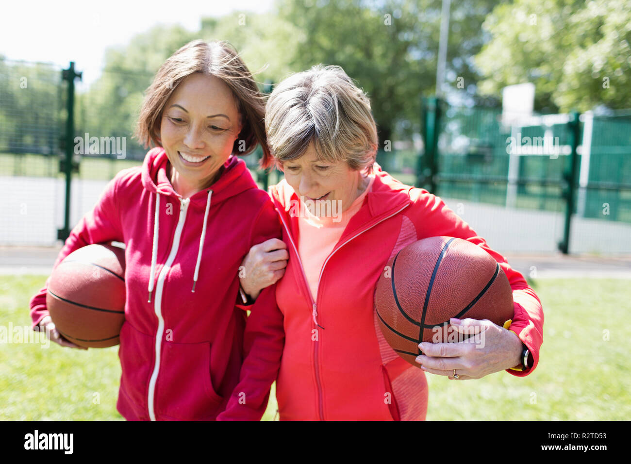 Attiva le donne senior amici giocare a basket nel soleggiato parco Foto Stock