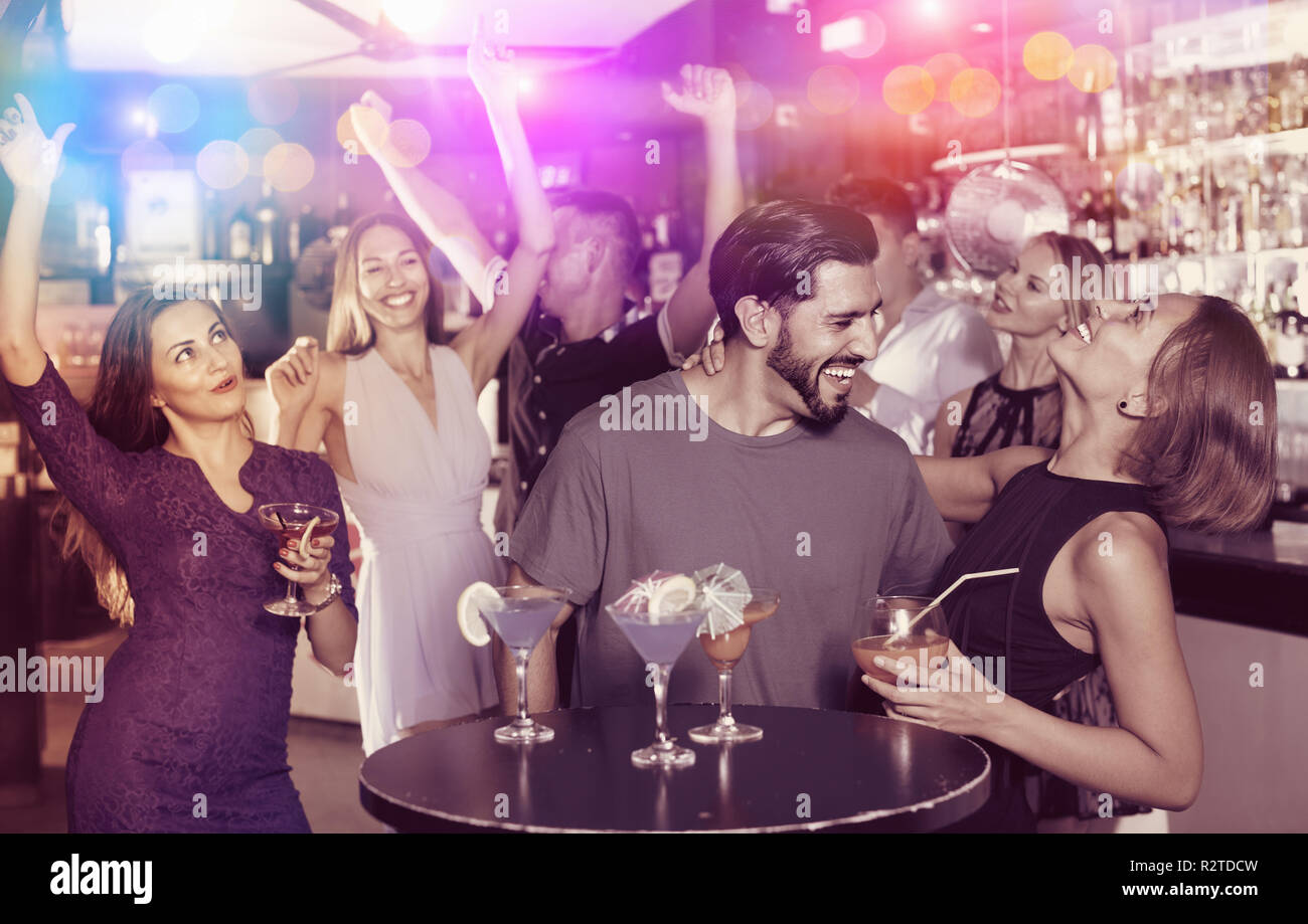 Allegro uomo positivo con giovani donne stanno godendo il partito in bar. Foto Stock