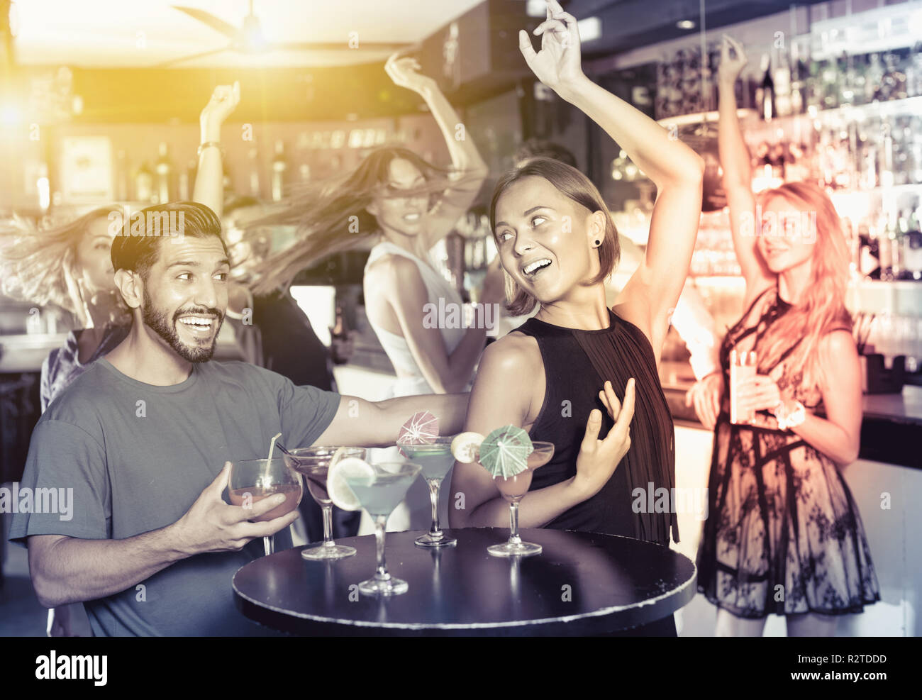 Positivo uomo sorridente con giovani donne stanno godendo il partito in bar. Foto Stock