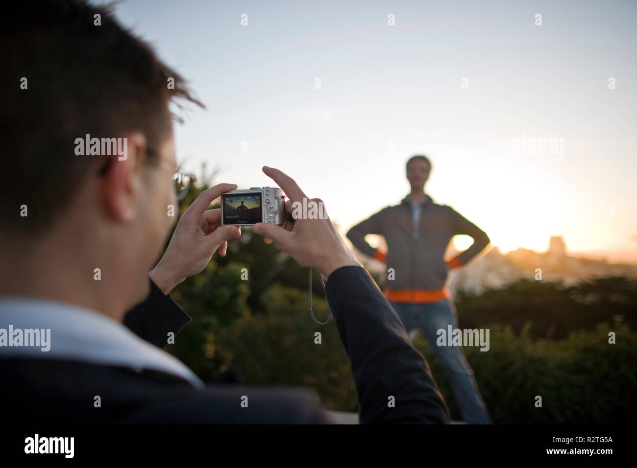 Giovane uomo di prendere una fotografia del suo amico su una fotocamera digitale. Foto Stock