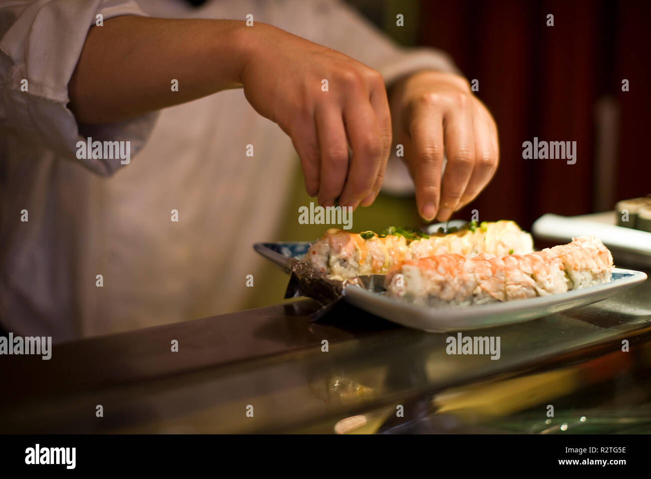 Guarnire essendo spruzzata su di un piatto di sushi. Foto Stock