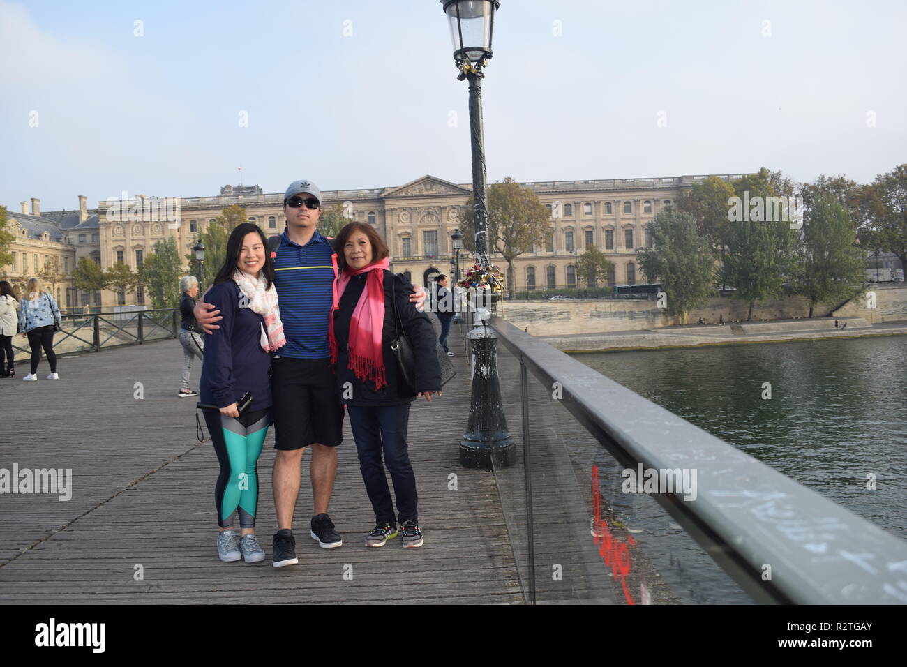 I popoli sul Pont des Arts passerella sul fiume Senna e la gente a piedi attraverso un ponte pedonale sul Fiume Senna di fronte al museo del Louvre Foto Stock