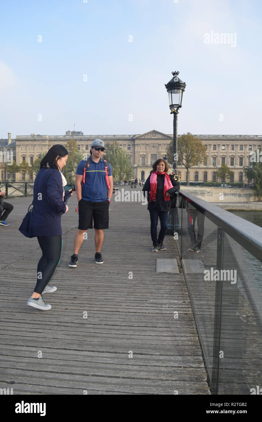 I popoli sul Pont des Arts passerella sul fiume Senna e la gente a piedi attraverso un ponte pedonale sul Fiume Senna di fronte al museo del Louvre Foto Stock