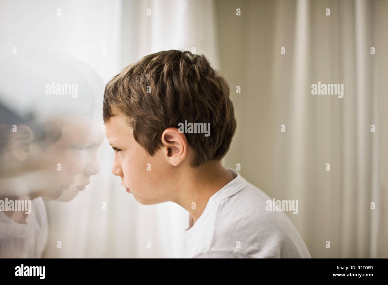 Ragazzo che guarda fuori della finestra Foto Stock