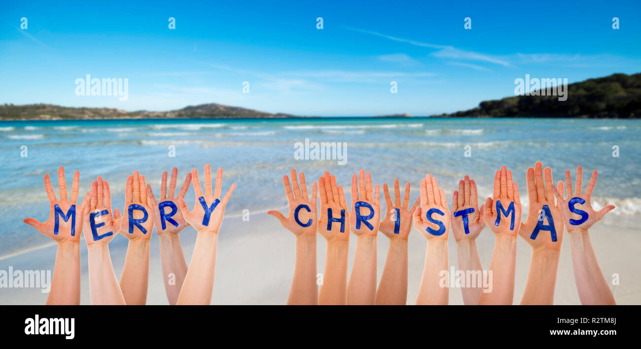 Molte mani la costruzione di parola Buon Natale, la spiaggia e l'oceano Foto Stock