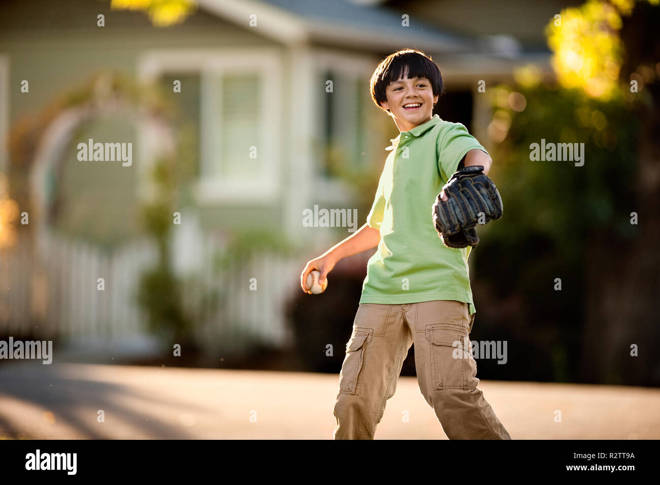 Sorridente giovane ragazzo a giocare a baseball in una strada suburbana. Foto Stock