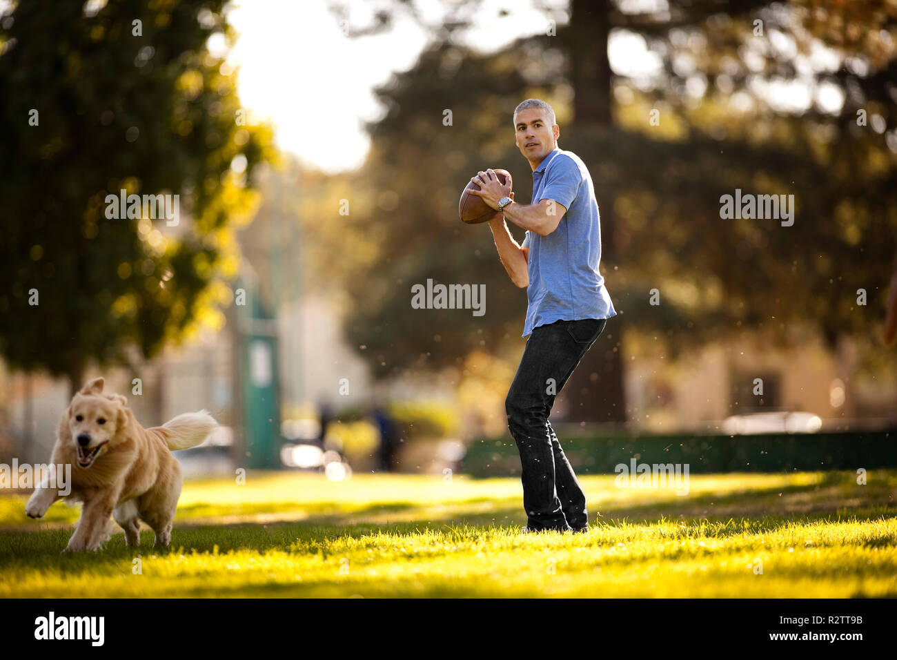 Uomo maturo preparando a lanciare un gioco del calcio mentre nel parco con il suo cane. Foto Stock