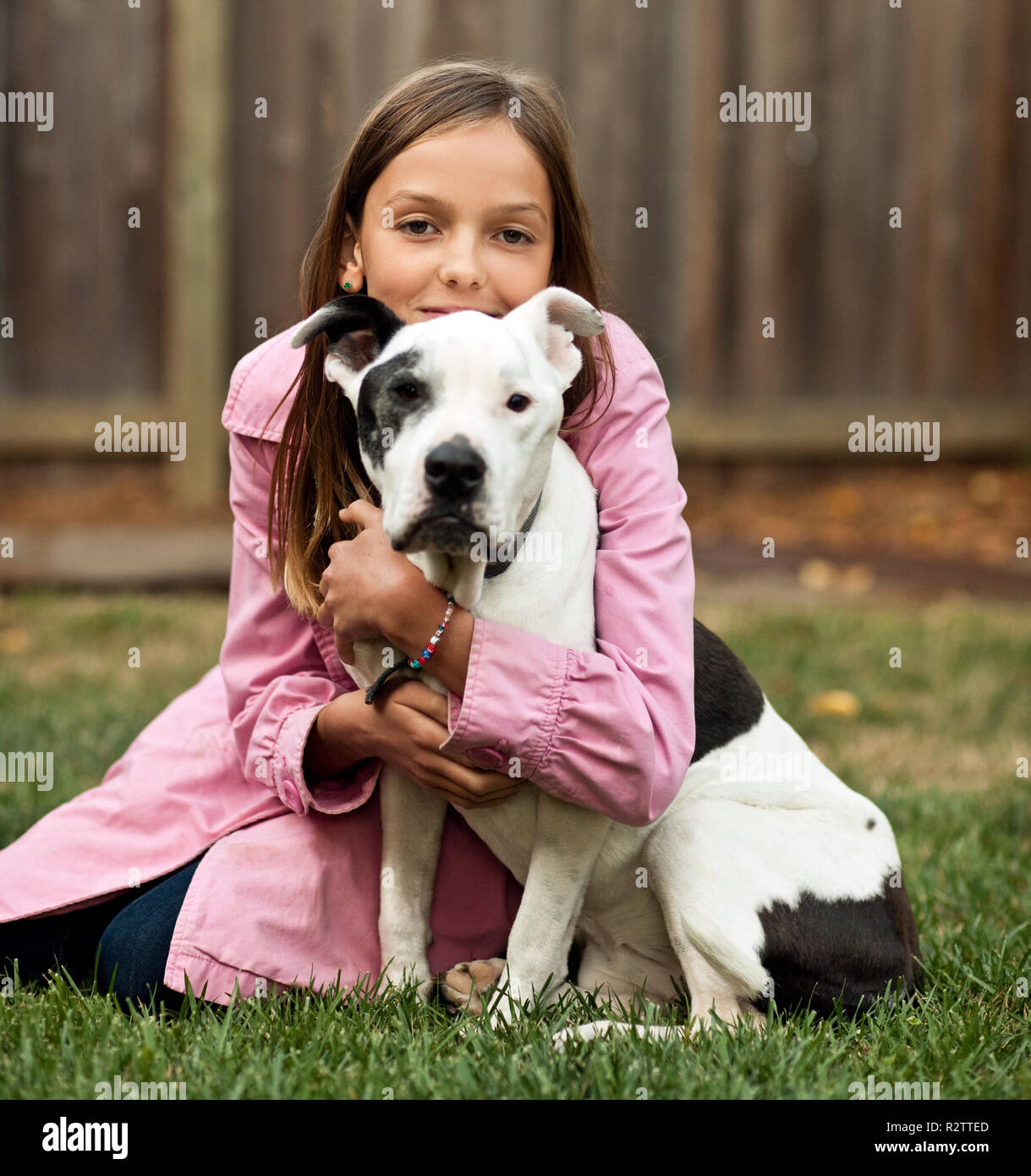 Ritratto di pre-teen ragazza seduta sul prato abbracciando il cane. Foto Stock