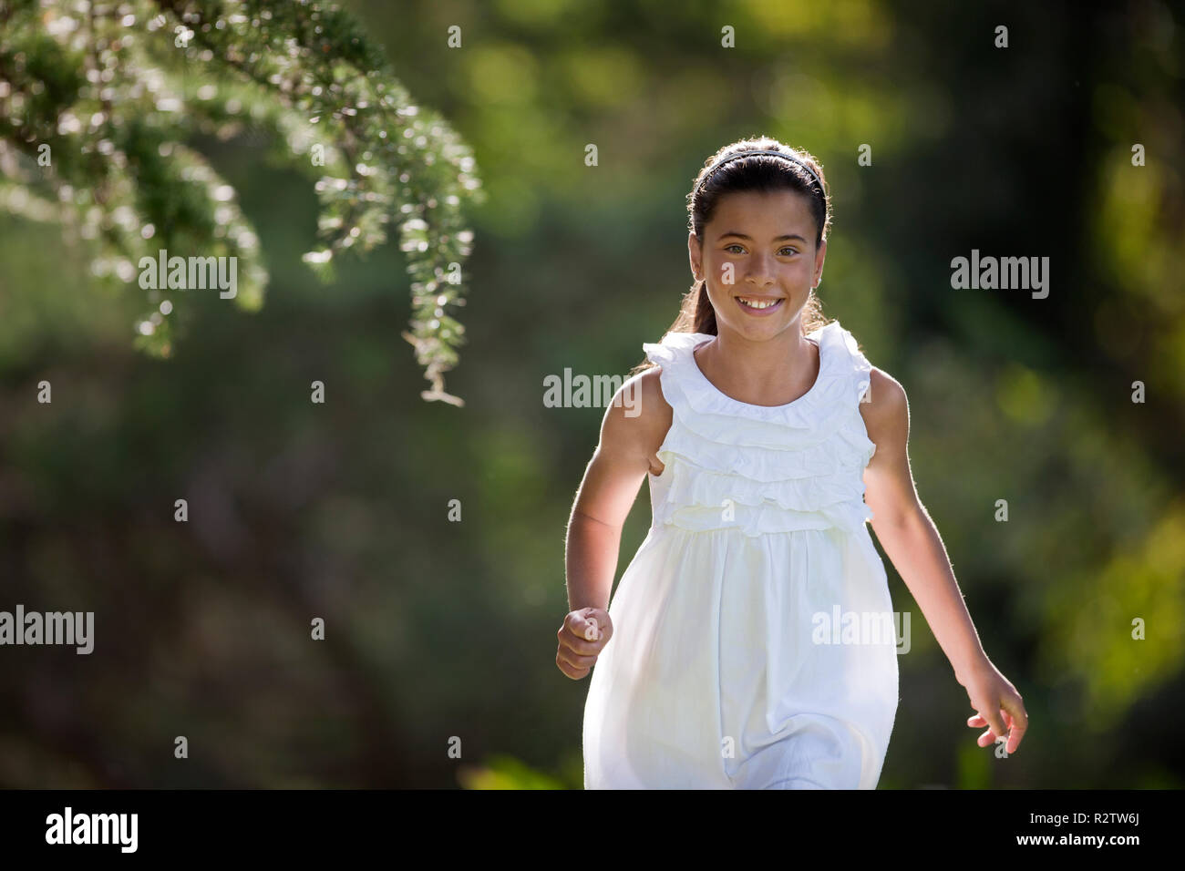 Ragazza sorride come lei corre attraverso un giardino e pone per un ritratto. Foto Stock