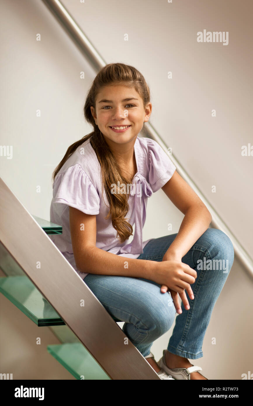Preteen sorrisi come si siede su una scala. Foto Stock