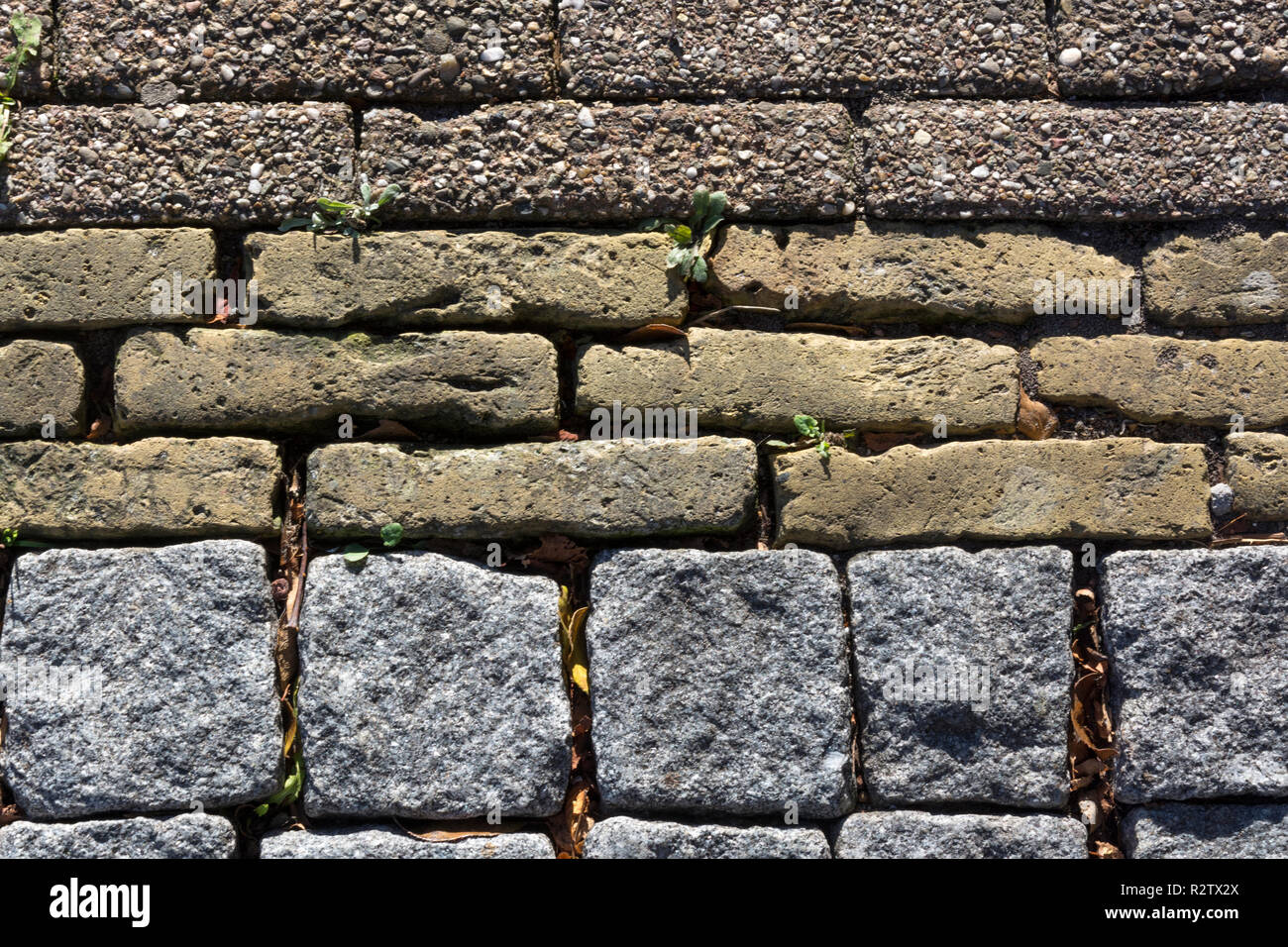 Motivo decorativo di tre diversi tipi di pietra utilizzati l'uno accanto all'altro. Per servire come una superficie per il traffico, un passaggio pedonale, un percorso o una strada. Foto Stock