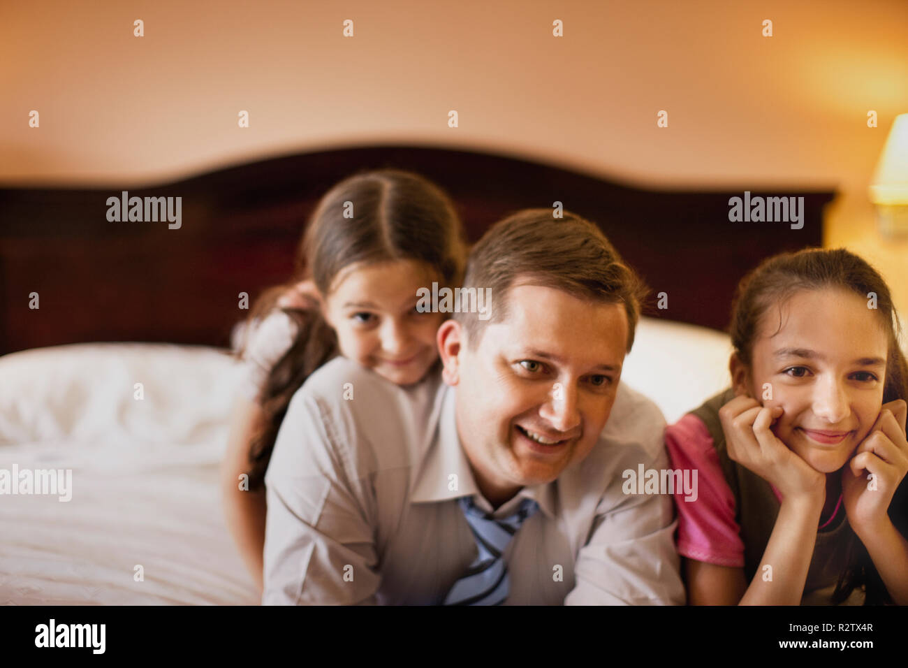 Due ragazze e il loro padre rilassante sul letto d'hotel. Foto Stock