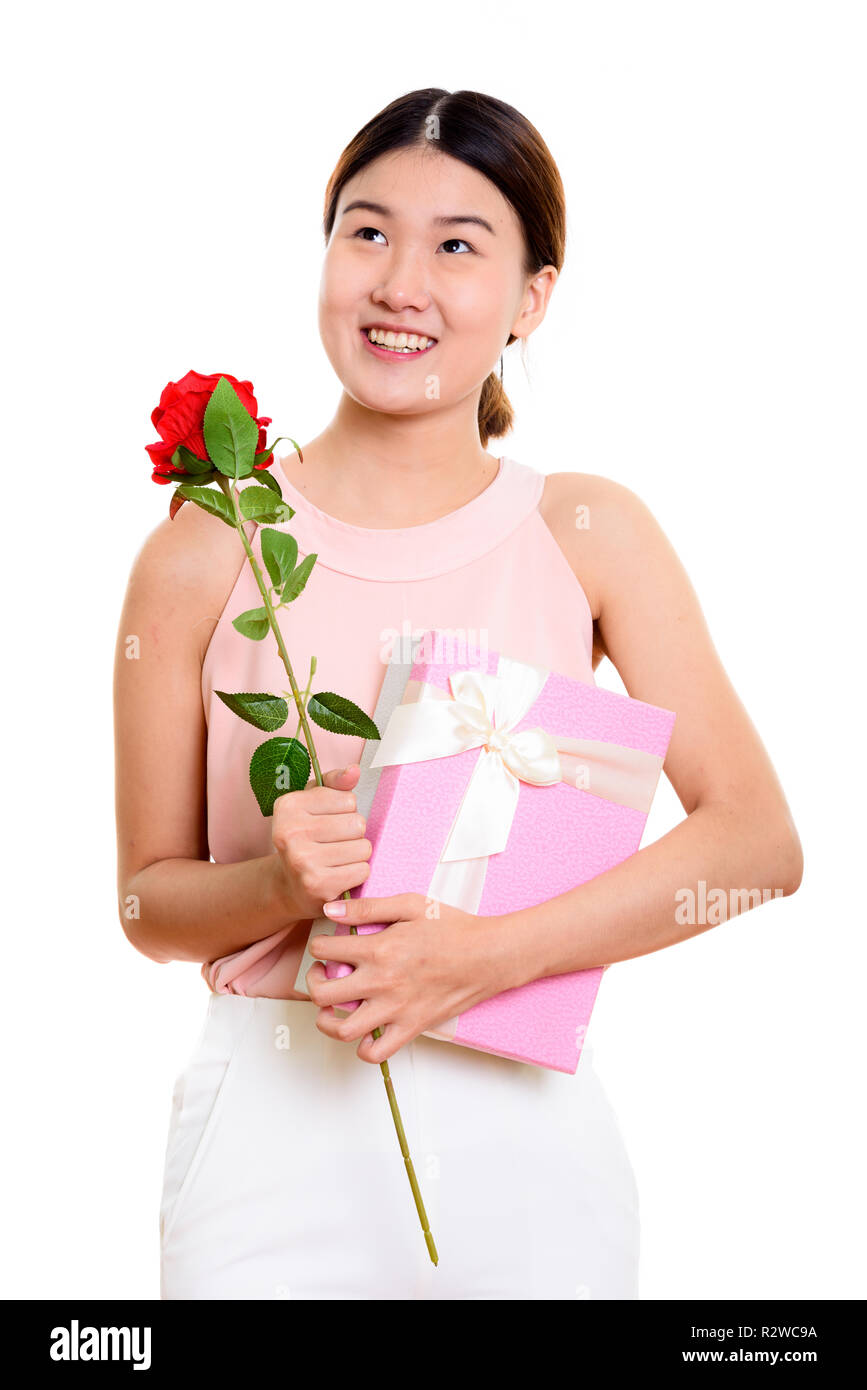 Felice giovane donna asiatica sorridente e pensare tenendo rosso r Foto Stock