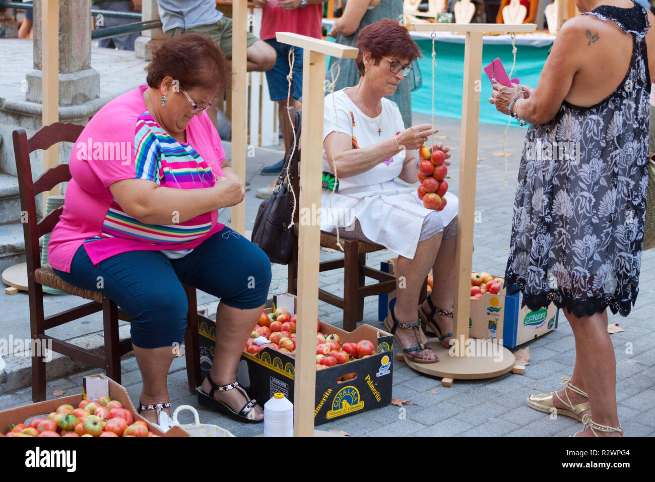 MARIA DE LA SALUT, MALLORCA, Spagna - 10 agosto 2018: le donne la legatura dei pomodori insieme per formare i grappoli pendenti durante il pomodoro 'Ramellet' fiera di notte Foto Stock