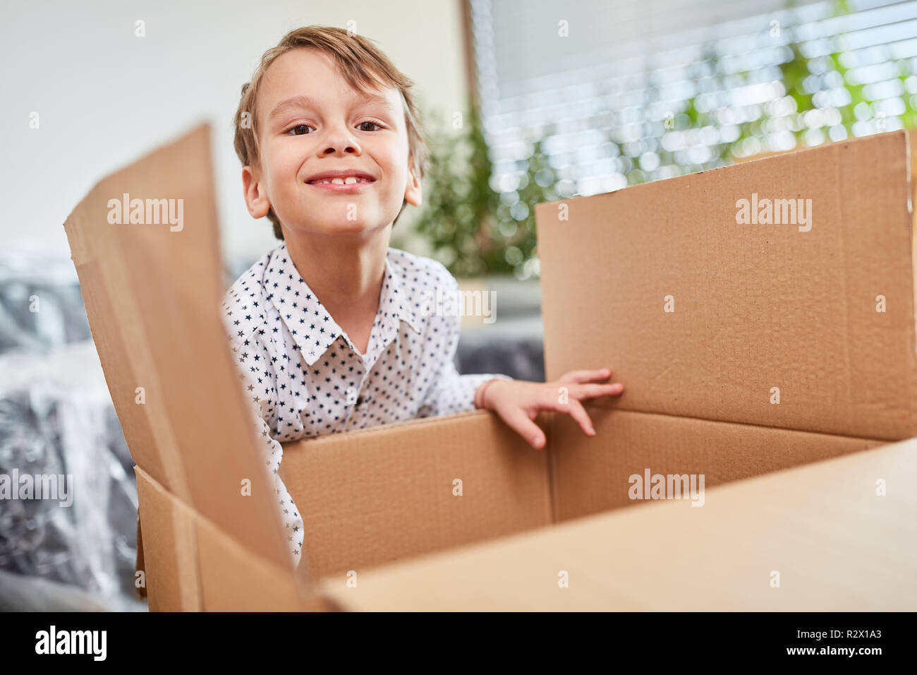 Felice ragazzo passando a casa con la scatola di movimentazione consente di imballaggio Foto Stock