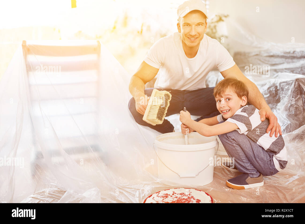 Figlio aiuta a suo padre un mix di colore per pittura mentre home lavori di rinnovo Foto Stock