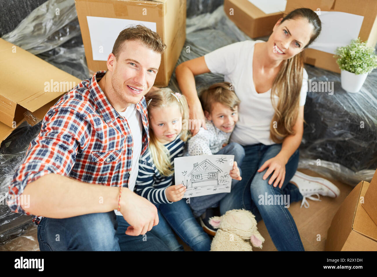 I genitori e i bambini con una foto della casa quando si sposta verso la nuova casa Foto Stock