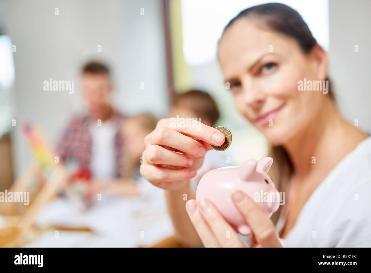 Donna con salvadanaio come un simbolo di finanziamento e di equità nella costruzione di una casa Foto Stock