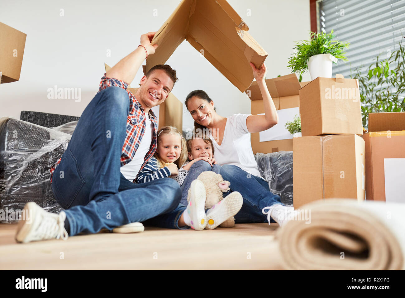 La famiglia felice sotto un tetto come il simbolo di una casa da sogno in futuro Foto Stock