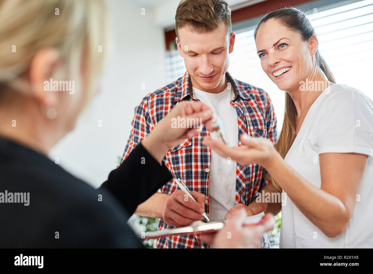 Felice coppia ottiene le chiavi per la casa e l uomo segni contratto di vendita Foto Stock