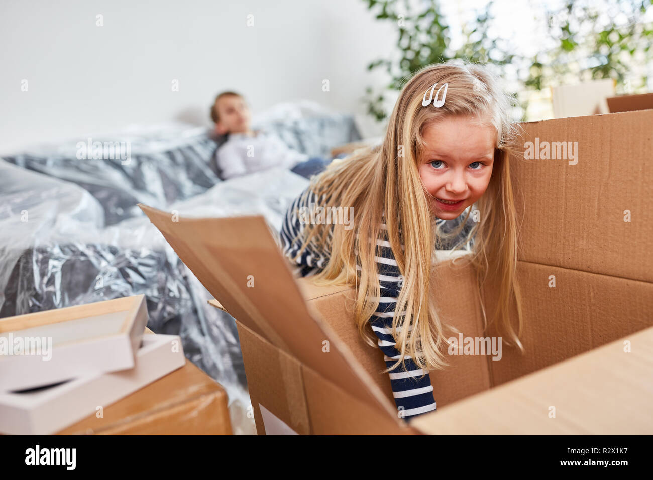 La ragazza estrae una scatola di movimentazione e aiuta con il passaggio alla nuova casa Foto Stock
