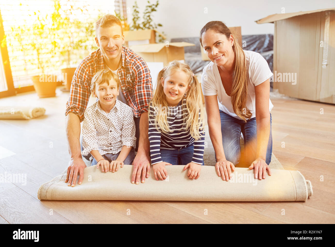 Genitori e figli Rotolo tappetino quando si sposta verso la nuova famiglia home Foto Stock