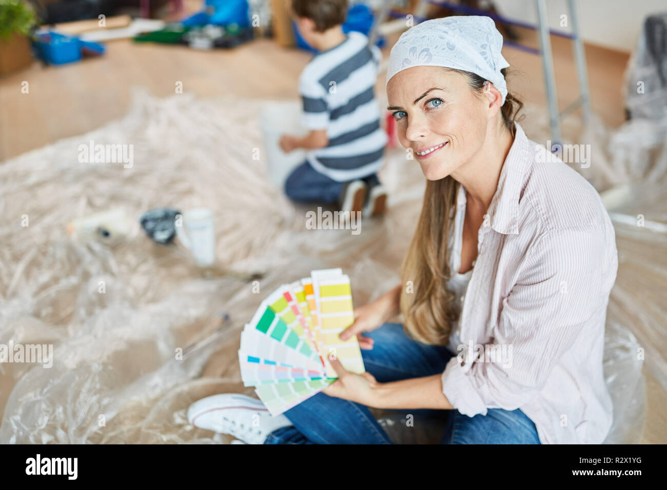 Donna con pattern per il muro di vernice durante il restauro e la pittura nella nuova casa Foto Stock
