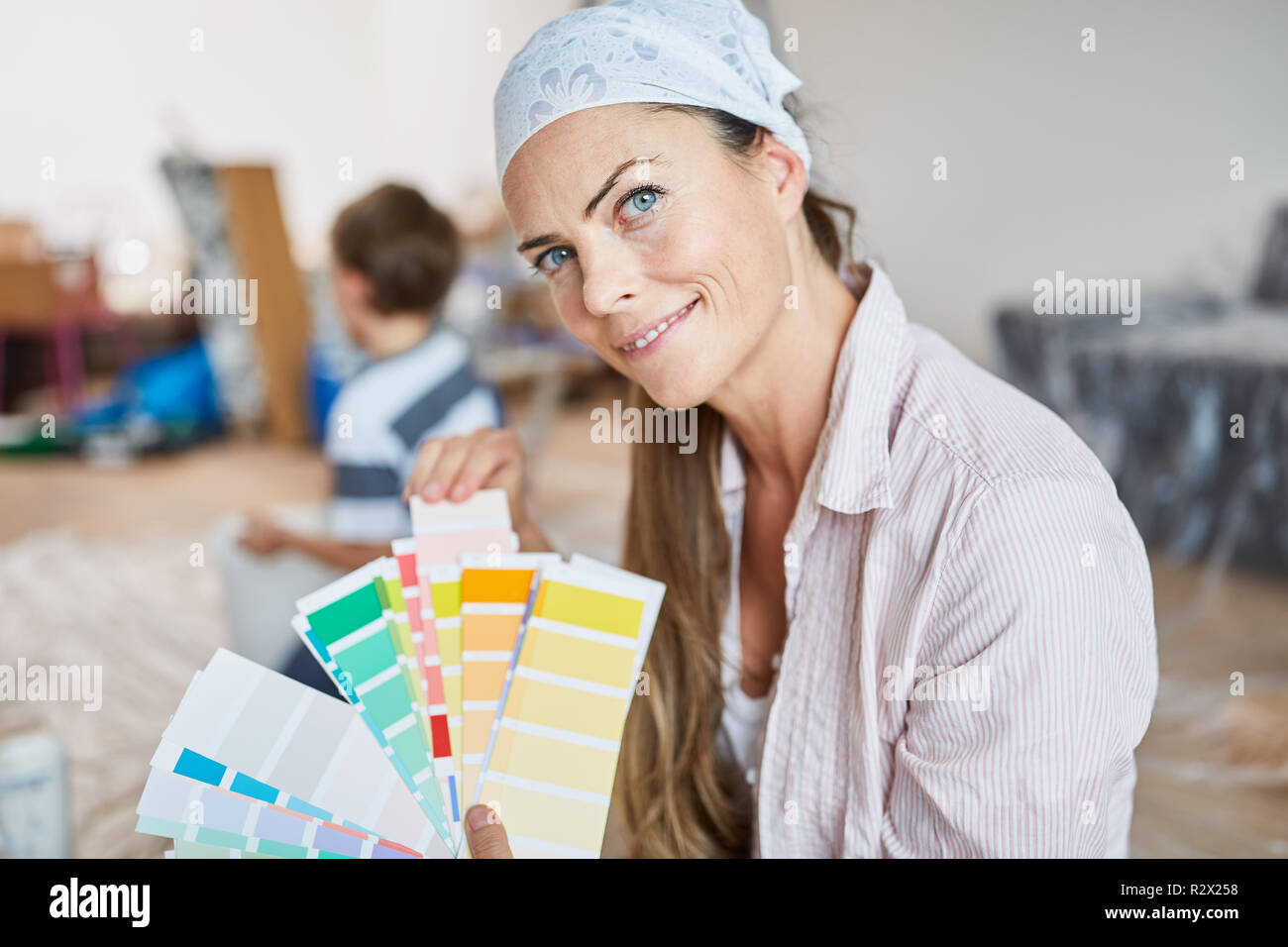 La donna come un tuttofare pittore scegliendo muro di vernice quando il rinnovamento Foto Stock