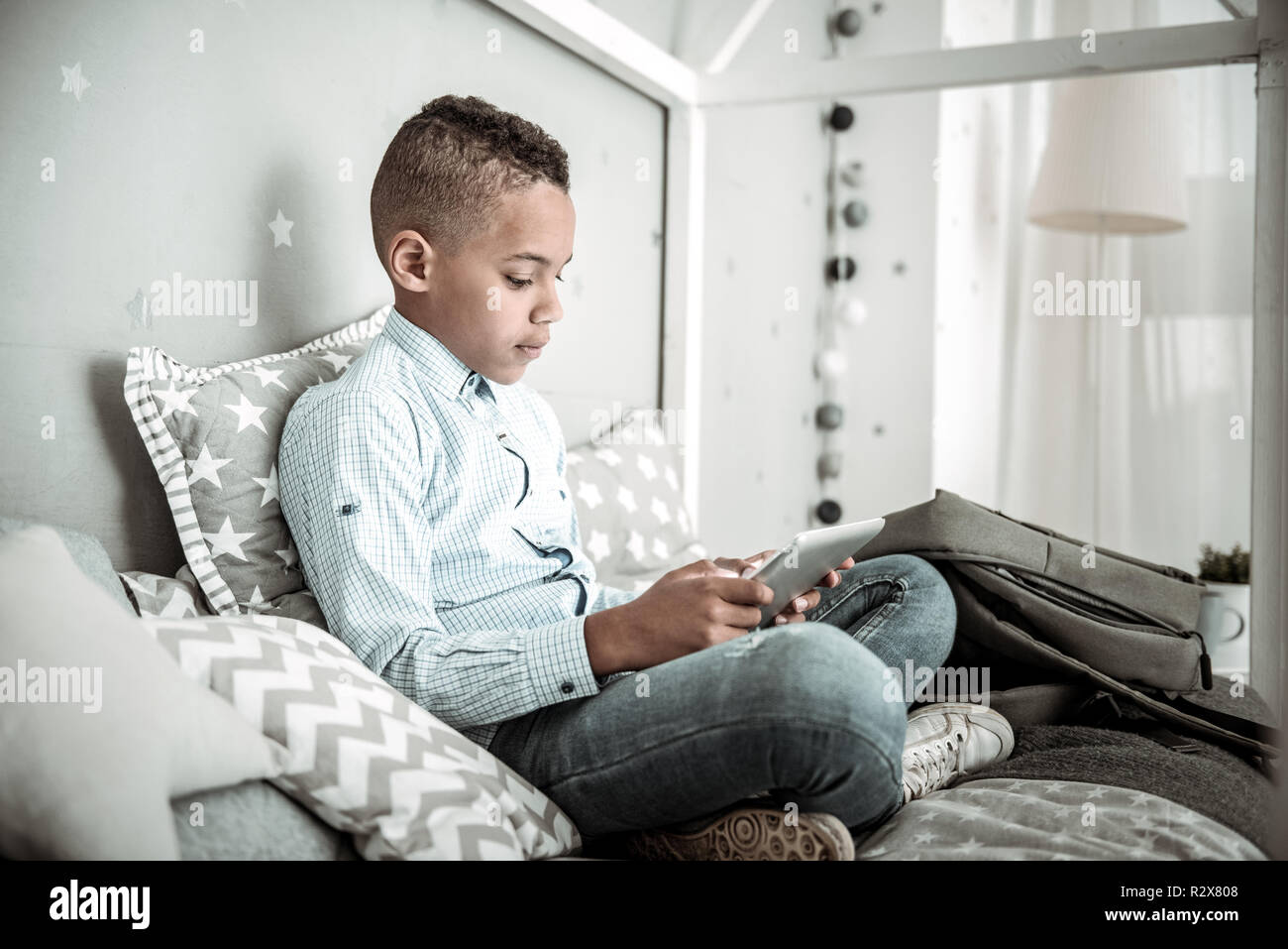 Piacevole carino ragazzo giocando sul suo tablet Foto Stock