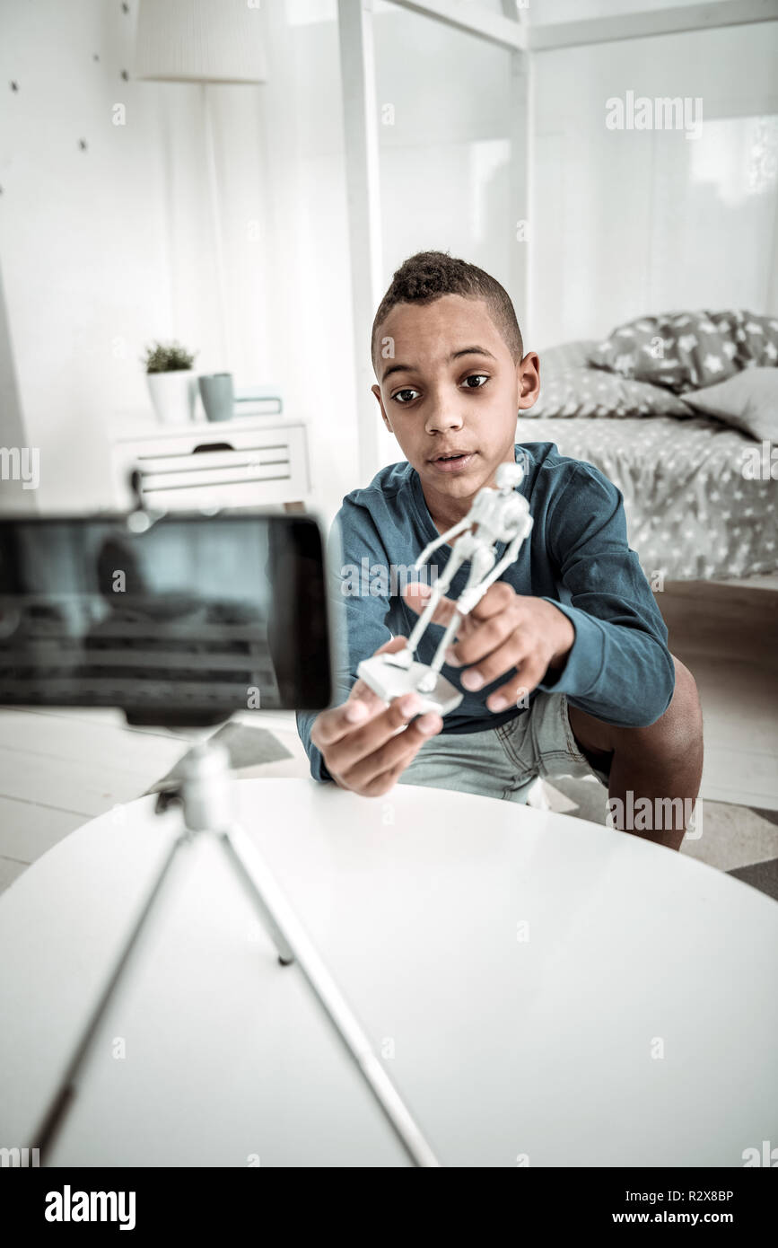 Piacevole bel ragazzo che mostra un modello di scheletro per la fotocamera Foto Stock