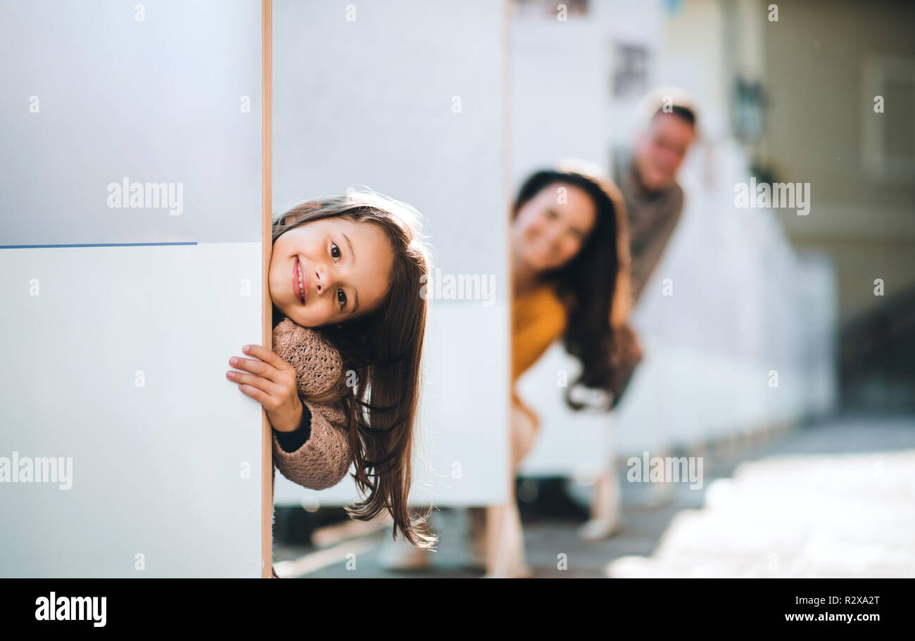 Una piccola ragazza con la sua famiglia avendo divertimento in città in autunno, in tempo per la famiglia. Foto Stock