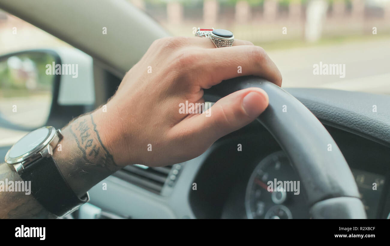 Un uomo con anelli sulla sua mano aziona un'auto. Canto close-up. Foto Stock Un uomo con anelli sulla sua mano aziona un'auto. Canto close-up. Foto Stock
