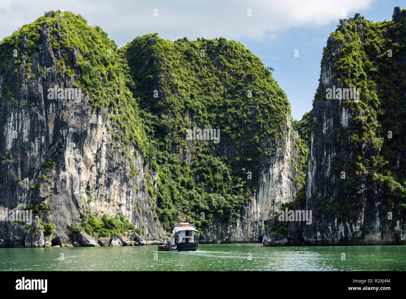Un turista vele di imbarcazioni tra facciata ripida roccia calcarea isole nella baia di Halong nel Mare della Cina del Sud. Ha Long, Quảng Ninh, Vietnam Asia Foto Stock