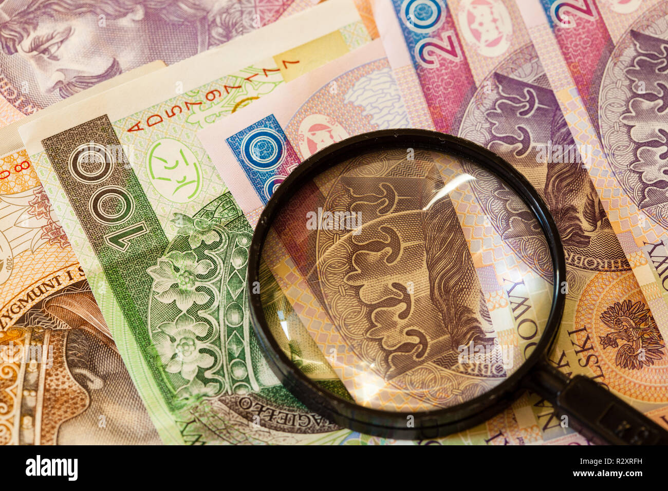 La contraffazione di denaro concetto. Zloty polacco banconote moneta e lente di ingrandimento Foto Stock