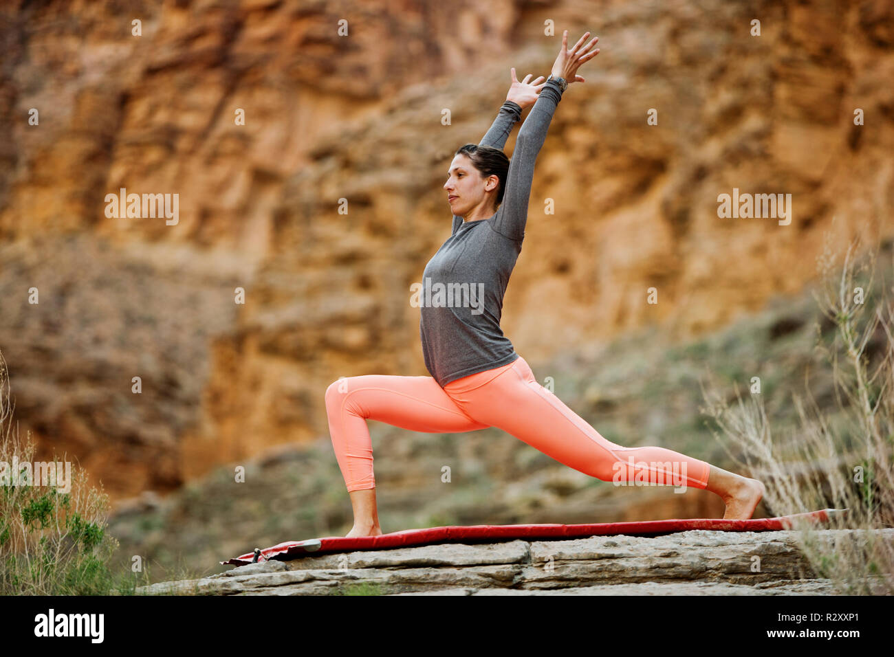 Giovane donna stretching su una roccia. Foto Stock