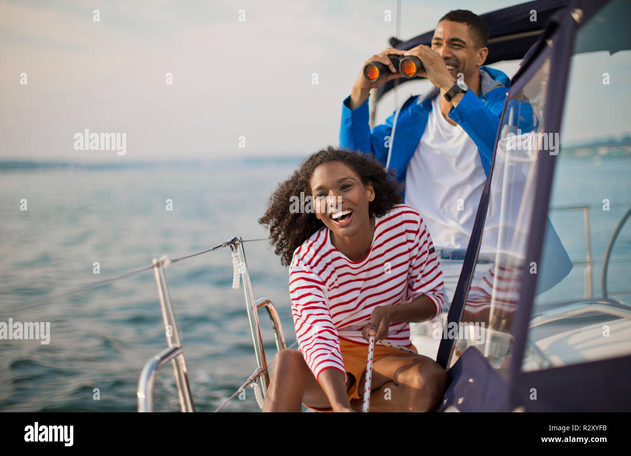 Felice coppia giovane divertendosi con un binocolo mentre la vela. Foto Stock
