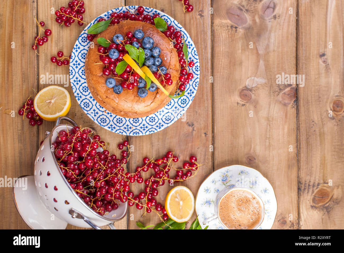 Pan di Spagna rotondo con ribes e mirtillo bacche su un tavolo di legno. Partite di frutti di bosco e aromatico caffè la mattina per la colazione. Spazio libero per il testo Foto Stock
