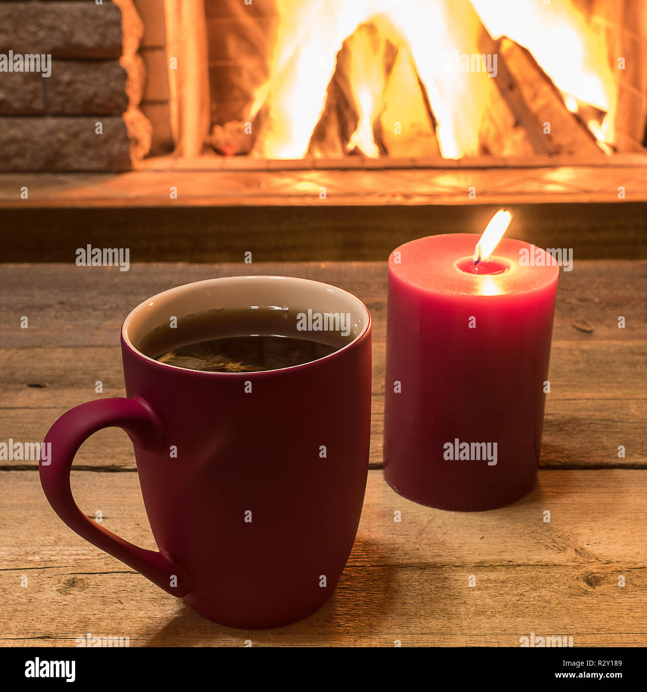 La tazza di tè caldo e candela vicino al caminetto, in country house, vacanza invernale, orizzontale. Foto Stock