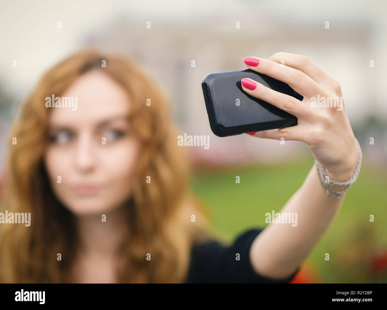 Giovane ragazza redhead prendendo un selfie all'aperto sulla giornata di sole. Foto Stock