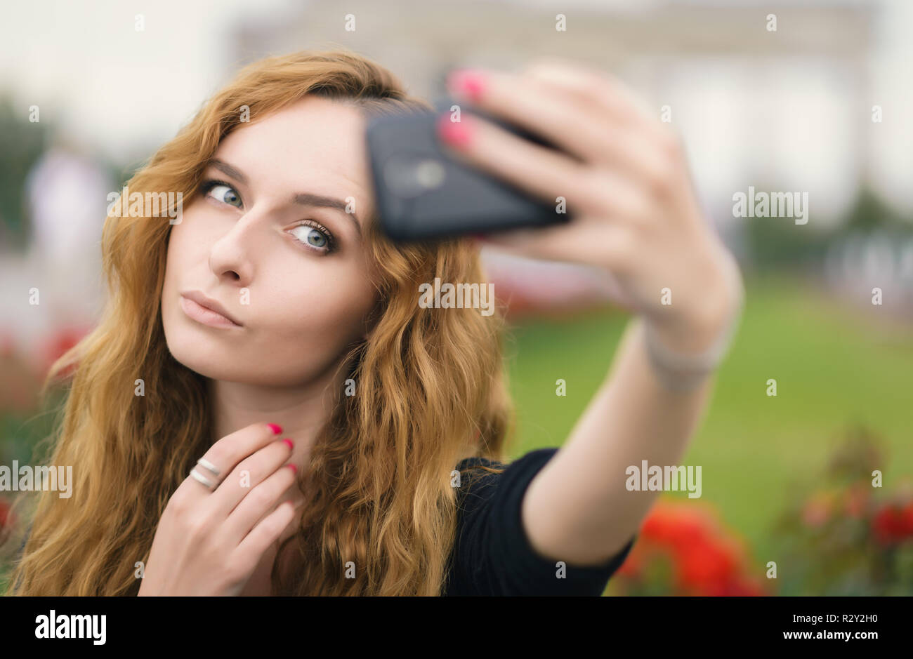 Giovane ragazza redhead prendendo un selfie all'aperto sulla giornata di sole. Foto Stock