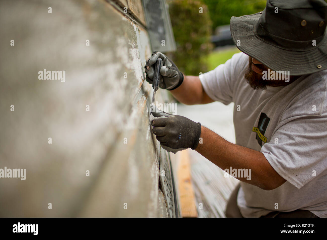 Lavoratore di raschiatura off di vernice di una vecchia casa a spiovente. Foto Stock